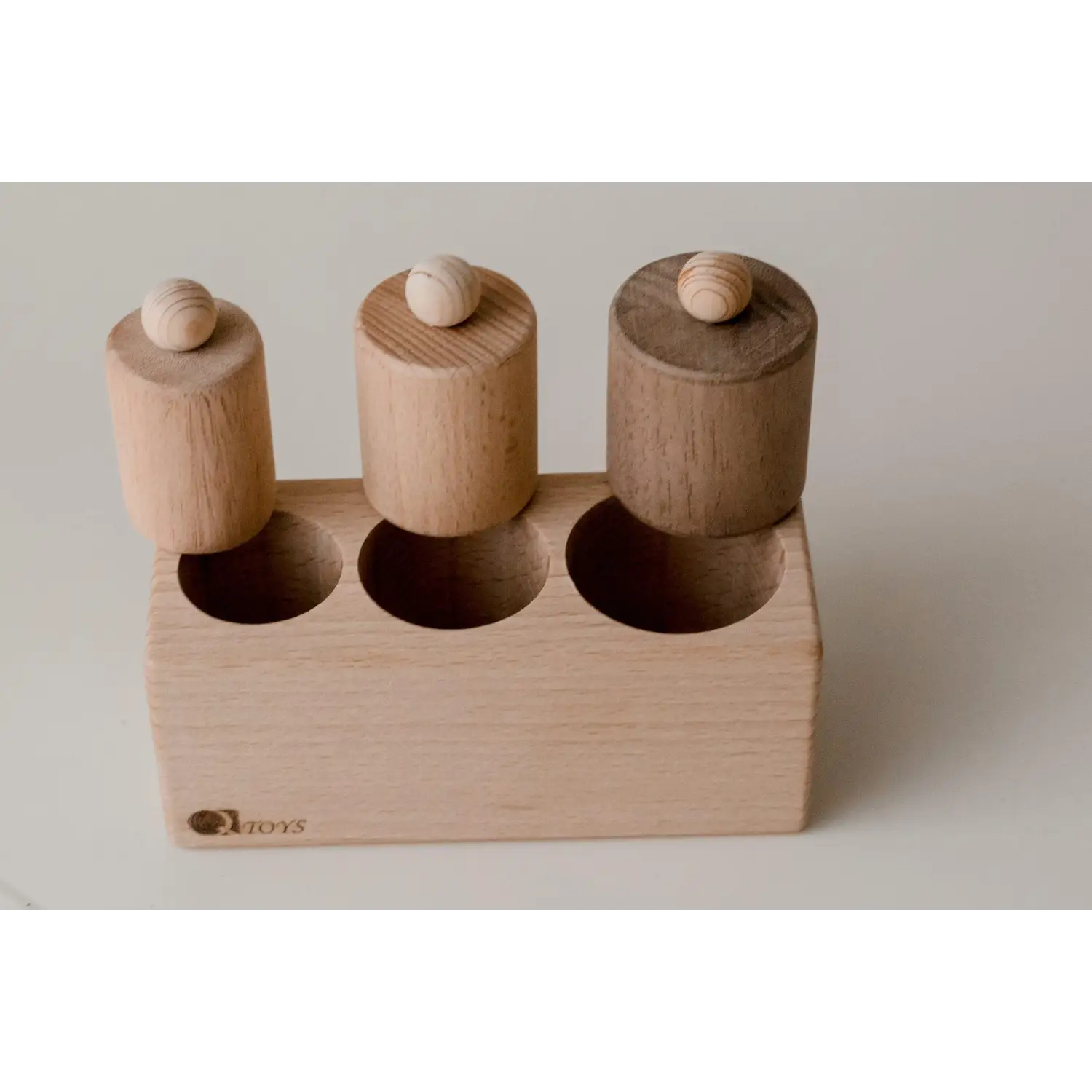 Wooden toy with three cylindrical pegs in a rectangular base.