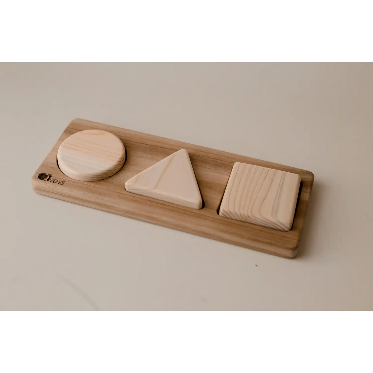 Wooden shape sorter toy with three geometric blocks.