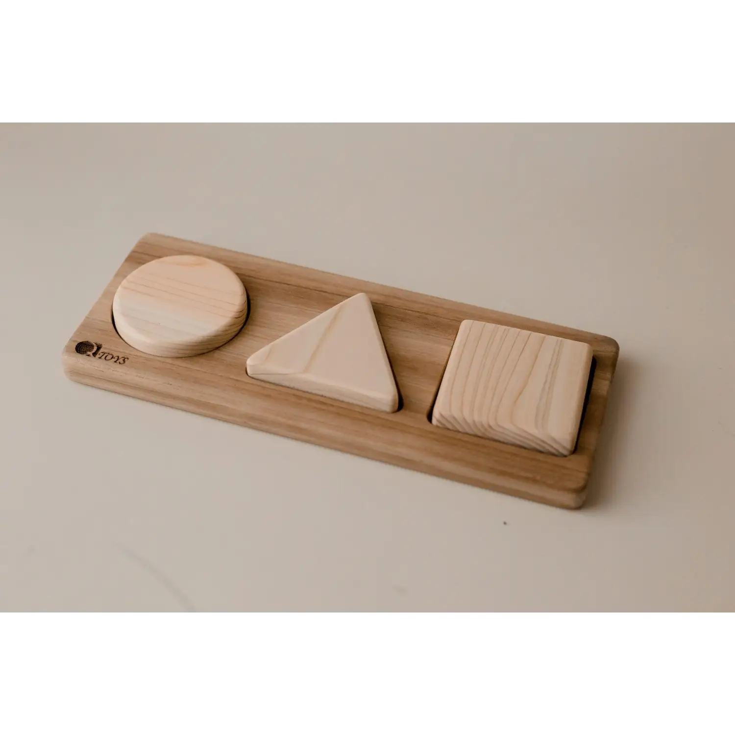 Wooden shape sorter toy with three geometric blocks.