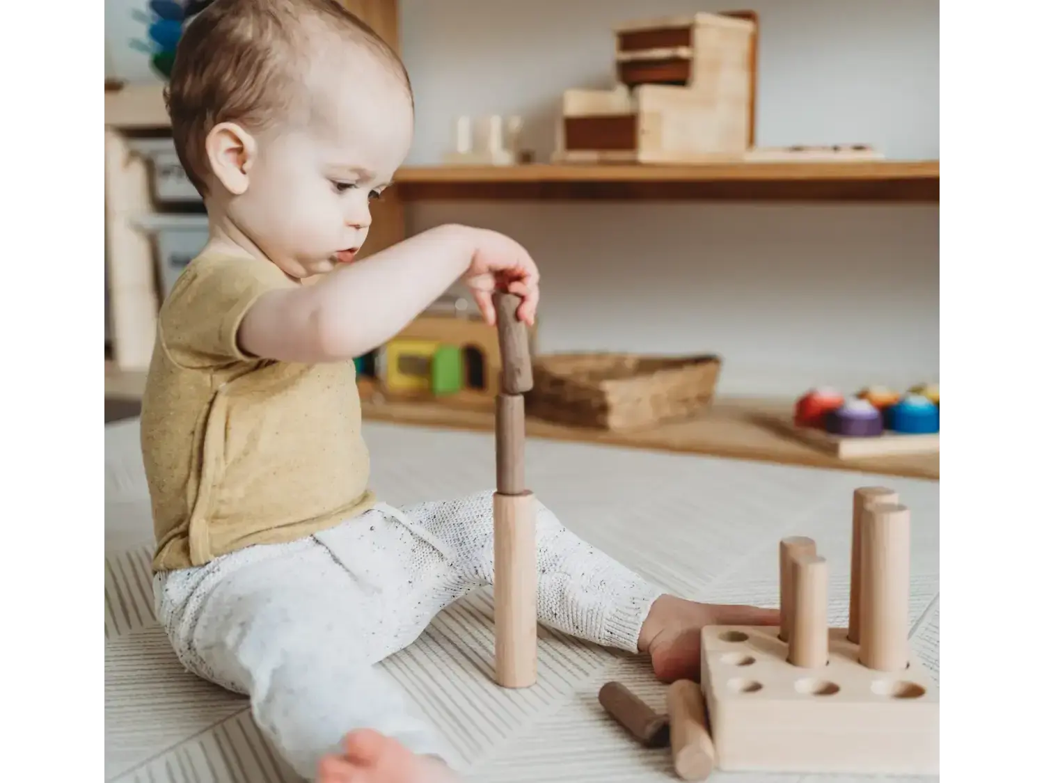 Young child playing with wooden building blocks on the floor.