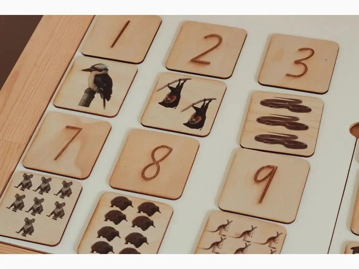 Wooden number and animal counting tiles arranged in a grid pattern.