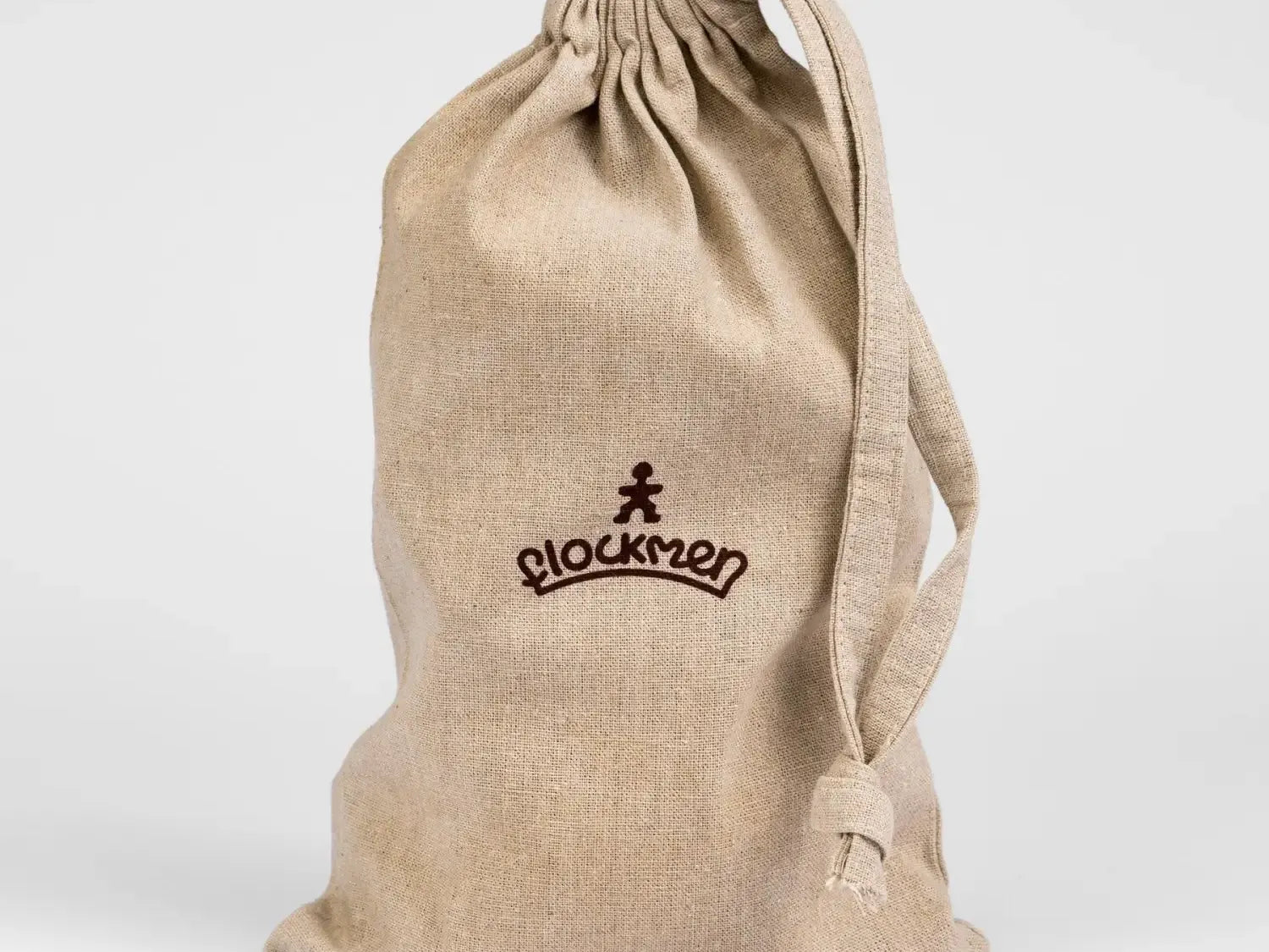 Beige drawstring bag with ’Blockmen’ logo printed on it.