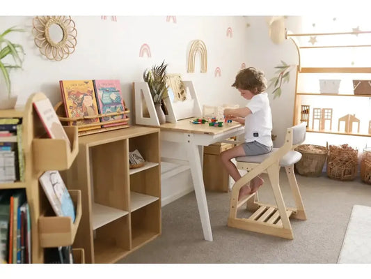 Child sitting at a wooden desk in a playroom or bedroom.