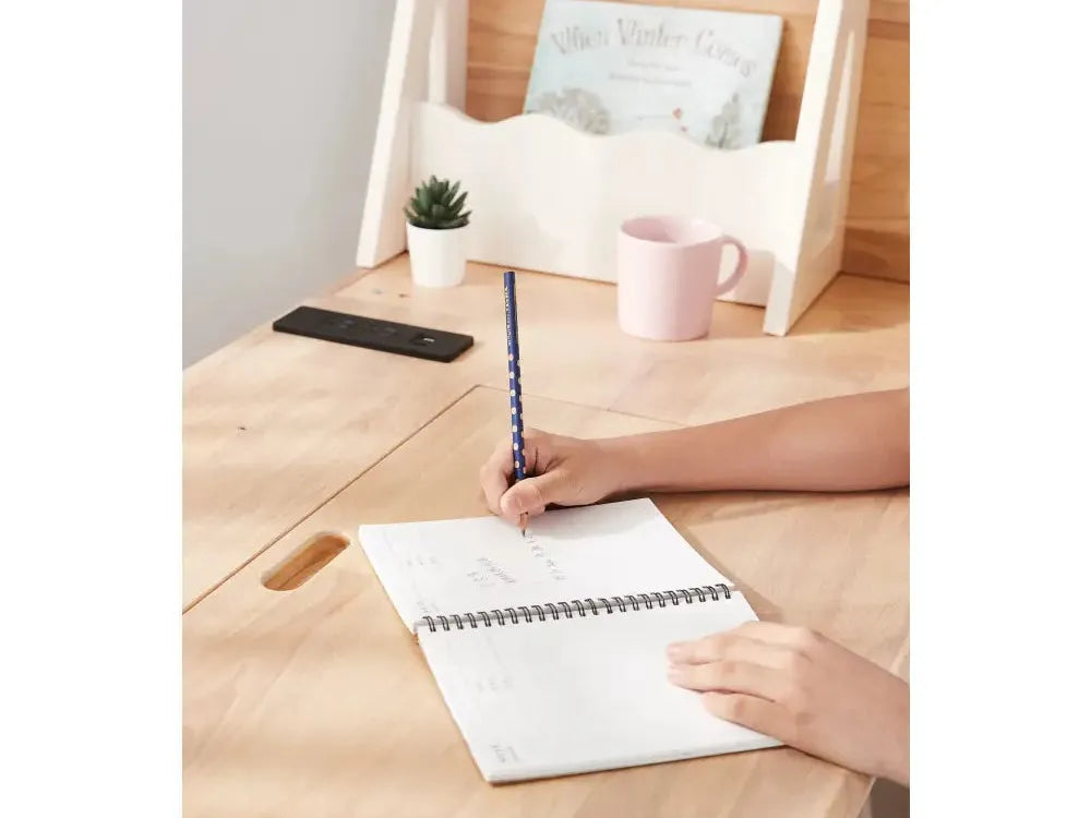 Wooden desk or table with a person’s hands writing in a notebook.