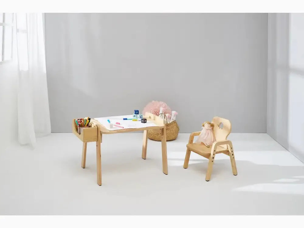 Wooden children’s desk and chair set with art supplies on the tabletop.