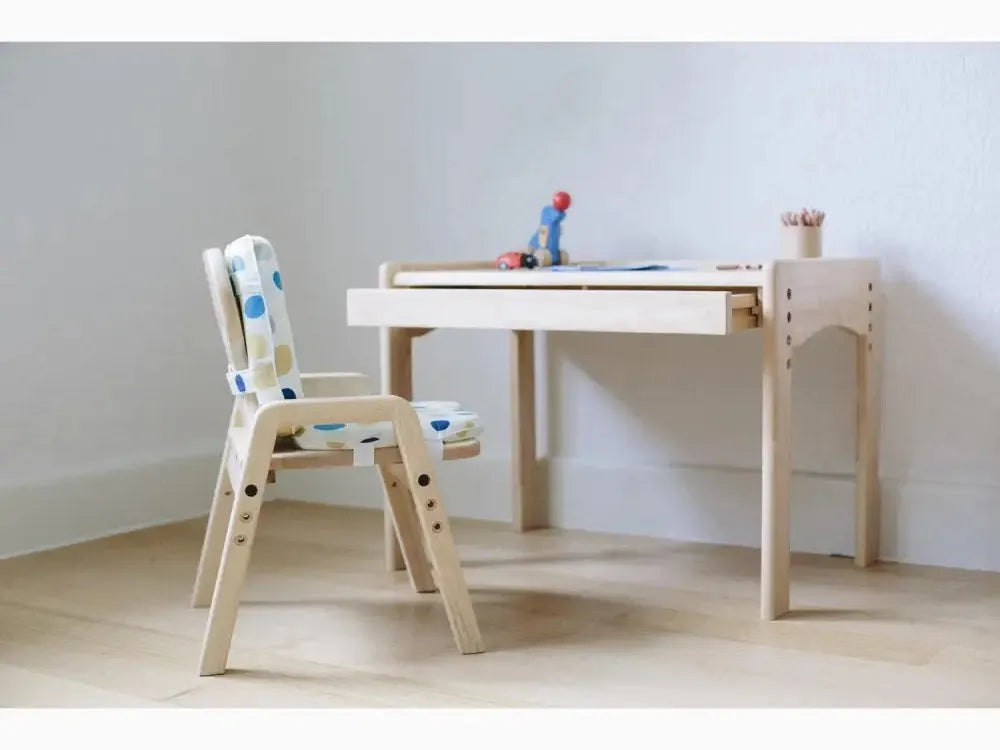 Children’s desk and chair set made of light-colored wood with colorful accents.