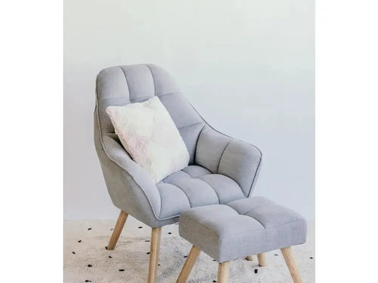 Comfortable-looking gray armchair with matching footstool and decorative pillow.