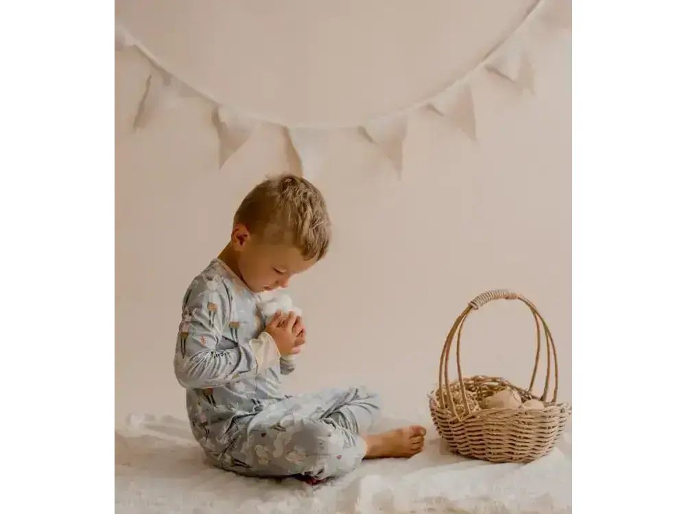 Young child sitting on the floor next to a wicker basket.