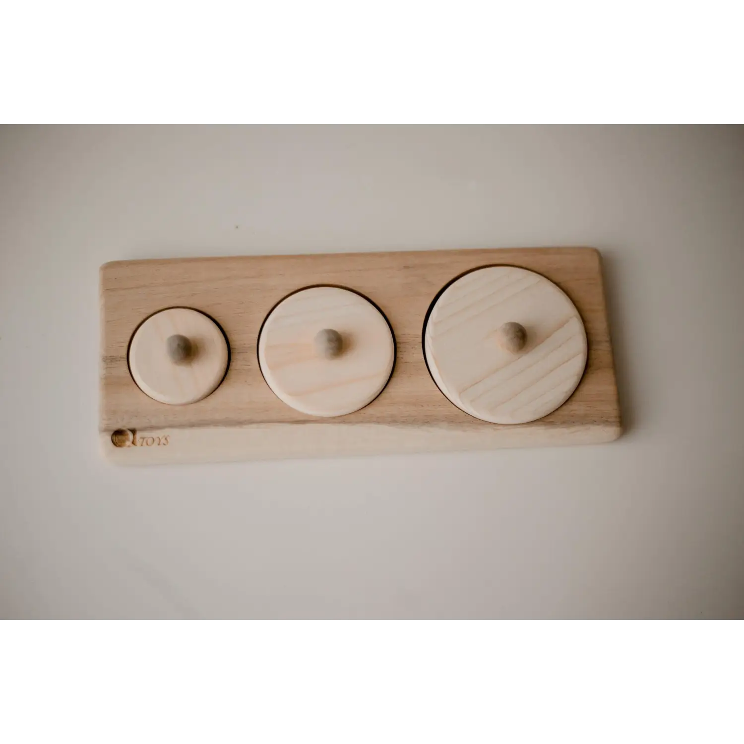 Wooden board with three circular indentations of varying sizes.