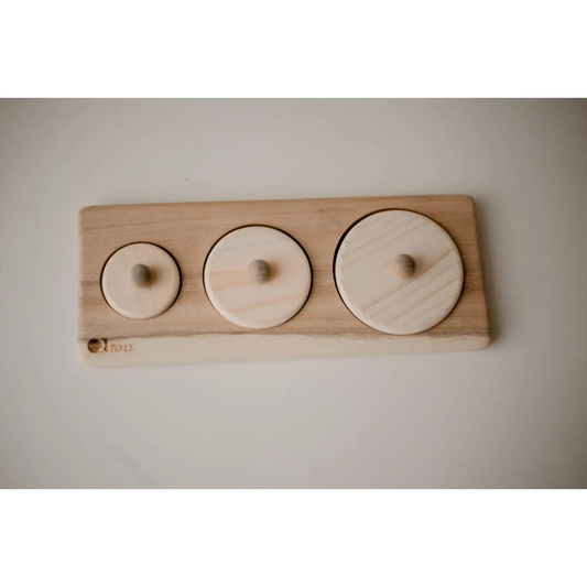 Wooden board with three circular indentations of varying sizes.