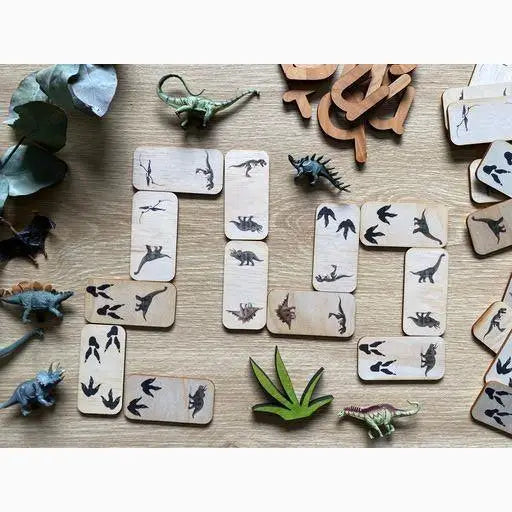 Wooden dominoes or tiles featuring dinosaur silhouettes and small dinosaur figurines.