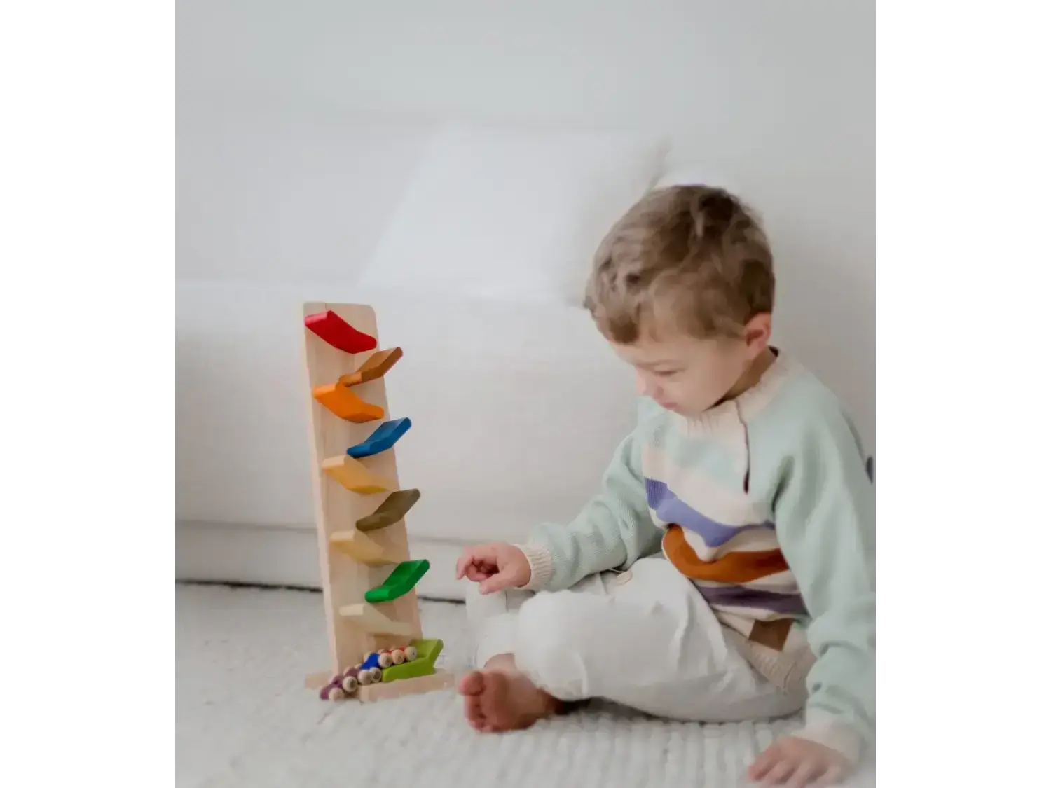 Young child playing with a colorful wooden toy track.