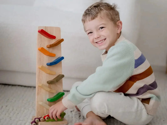 Smiling young child sitting on a carpet with a wooden toy.