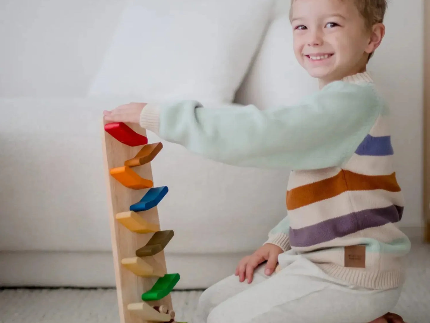 Smiling child playing with a colorful wooden stacking toy.
