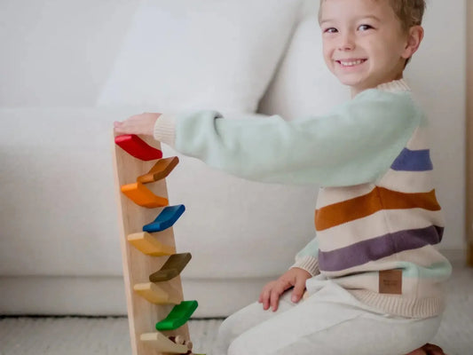 Smiling child playing with a colorful wooden stacking toy.