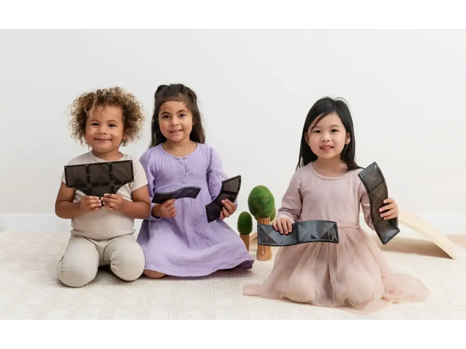 Three young girls sitting on the floor holding electronic tablets.