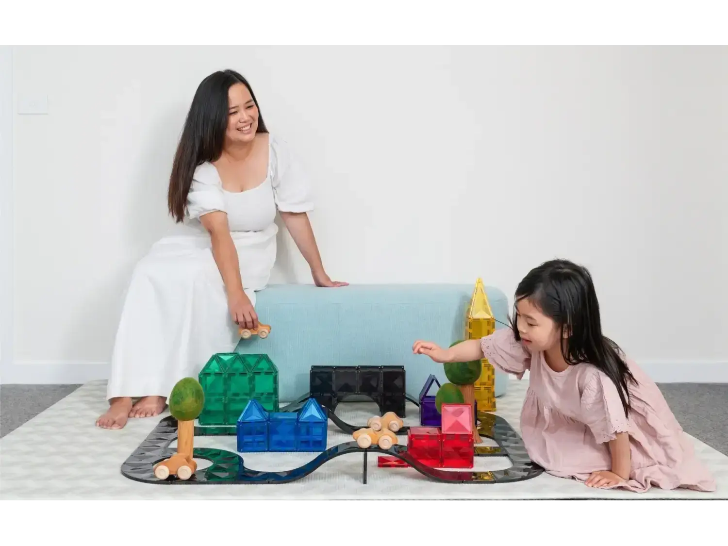 Woman and child playing with colorful building blocks and toys on the floor.
