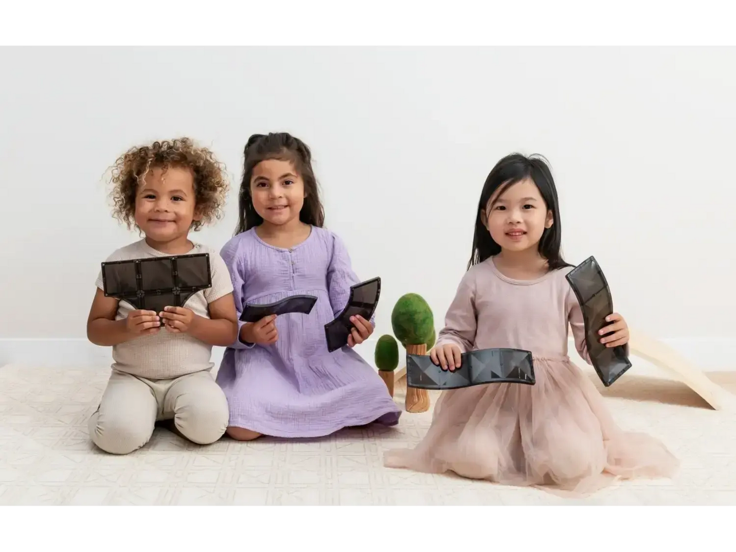 Three young girls sitting on the floor holding electronic tablets.