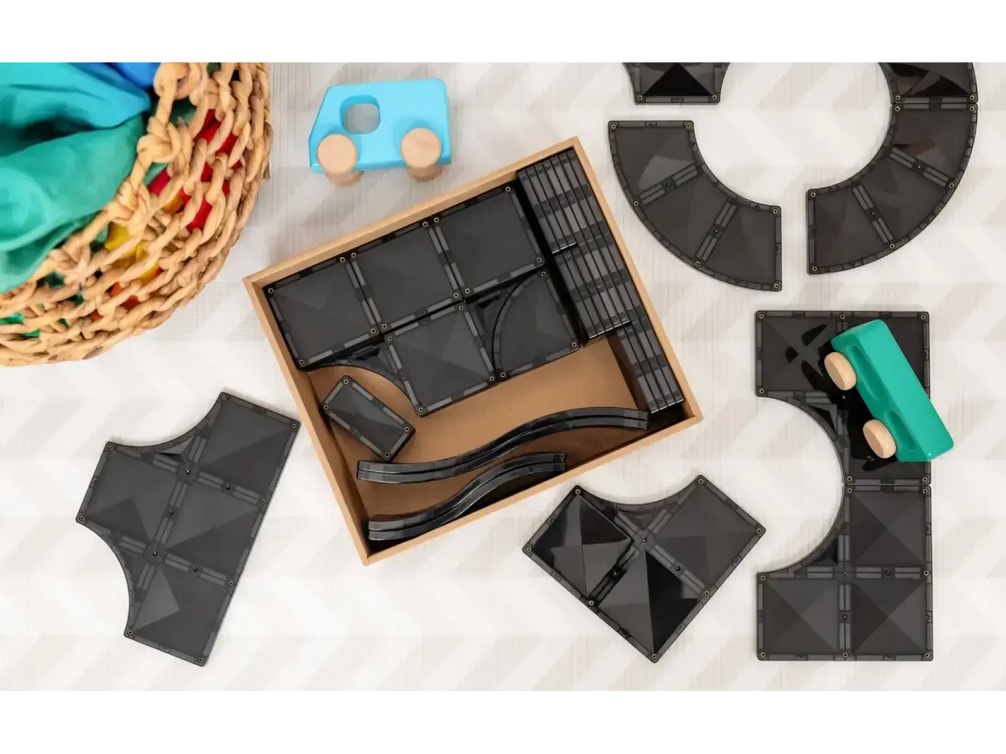 Wooden box containing dark-colored tangram puzzle pieces.