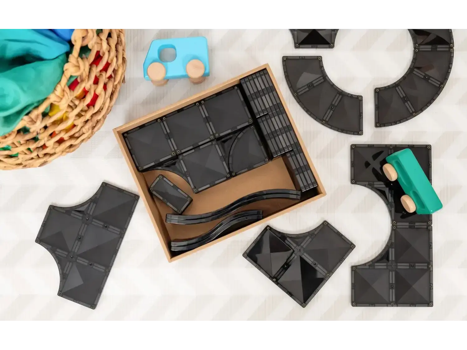 Wooden box containing dark-colored tangram puzzle pieces.