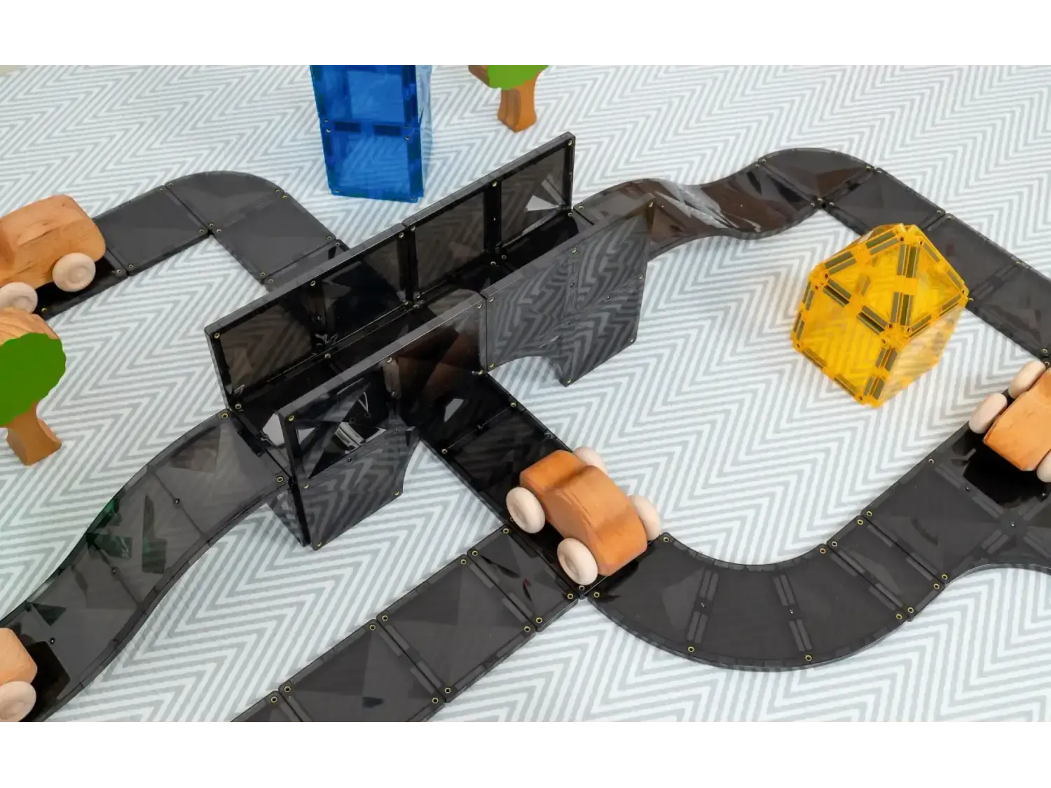 Toy road or racetrack with colorful vehicles and a bridge.