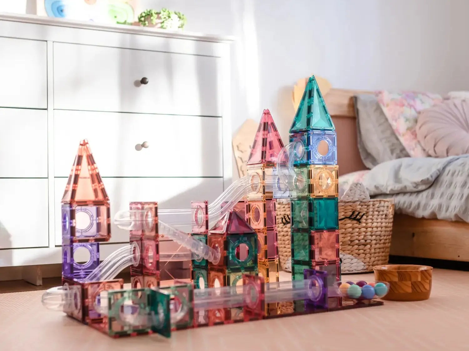 Colorful magnetic tile building set arranged into castle-like structures on the floor.