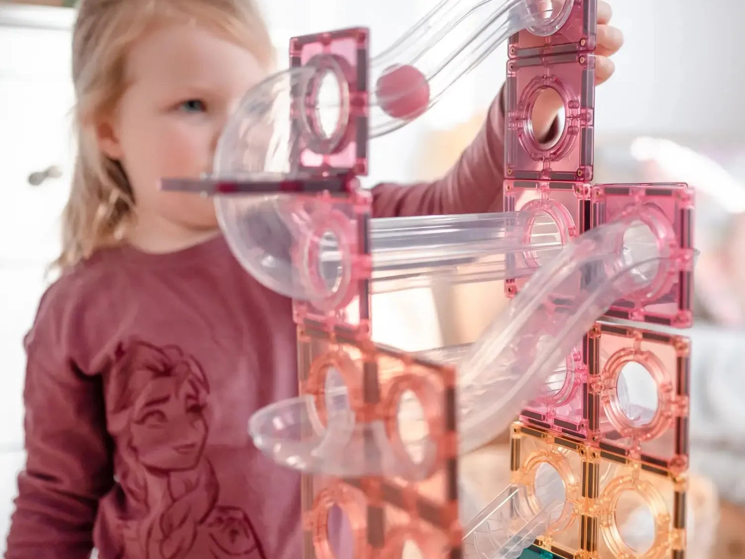 Colorful magnetic building tiles with transparent tubes and a small red ball.
