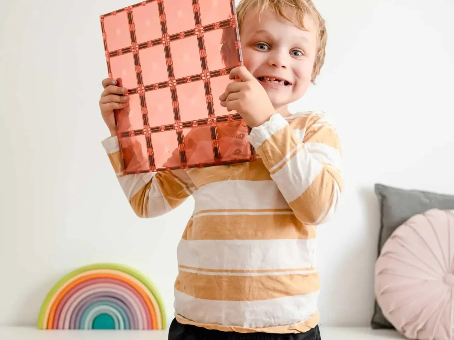 Smiling child holding a giant chocolate bar-shaped object.
