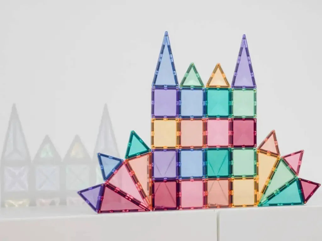 Colorful geometric construction made of translucent magnetic tiles arranged in a castle-like shape.