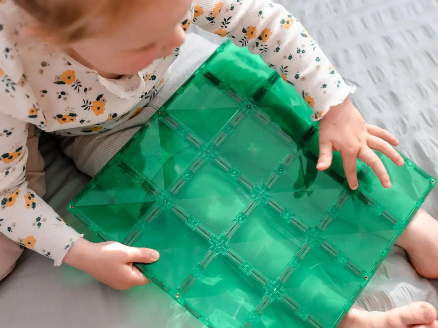 Green sensory mat with square-shaped compartments filled with liquid.