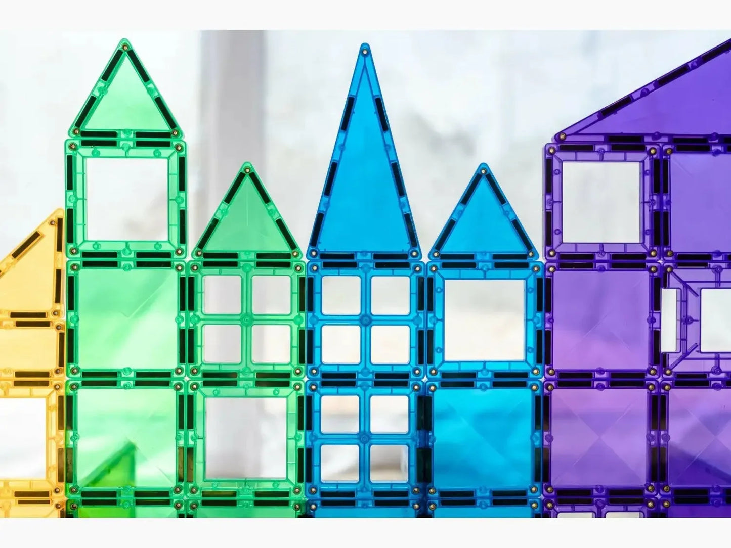 Colorful magnetic building tiles arranged to form house-like shapes.