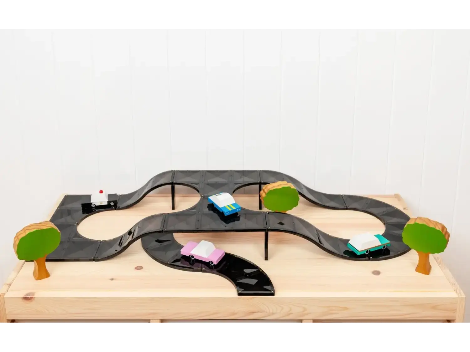 Wooden toy car track with miniature vehicles and trees.