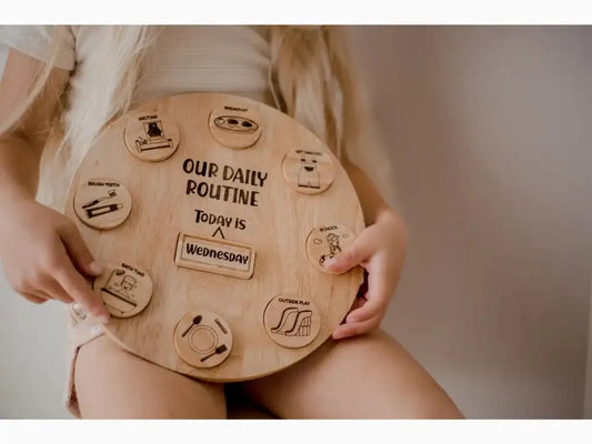 Wooden circular board with ’Our Daily Routine’ text and various icons representing daily activities.