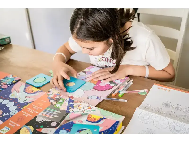 Child engaged in a colorful arts and crafts project at a table.