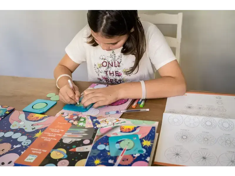 Young girl working on a colorful craft or art project at a table.