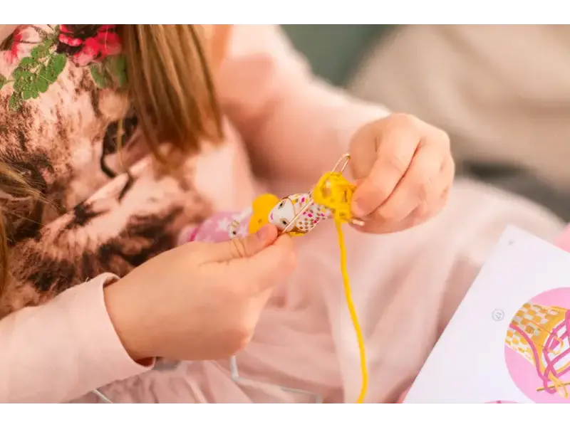 Kitten being adorned with a yellow ribbon or string.