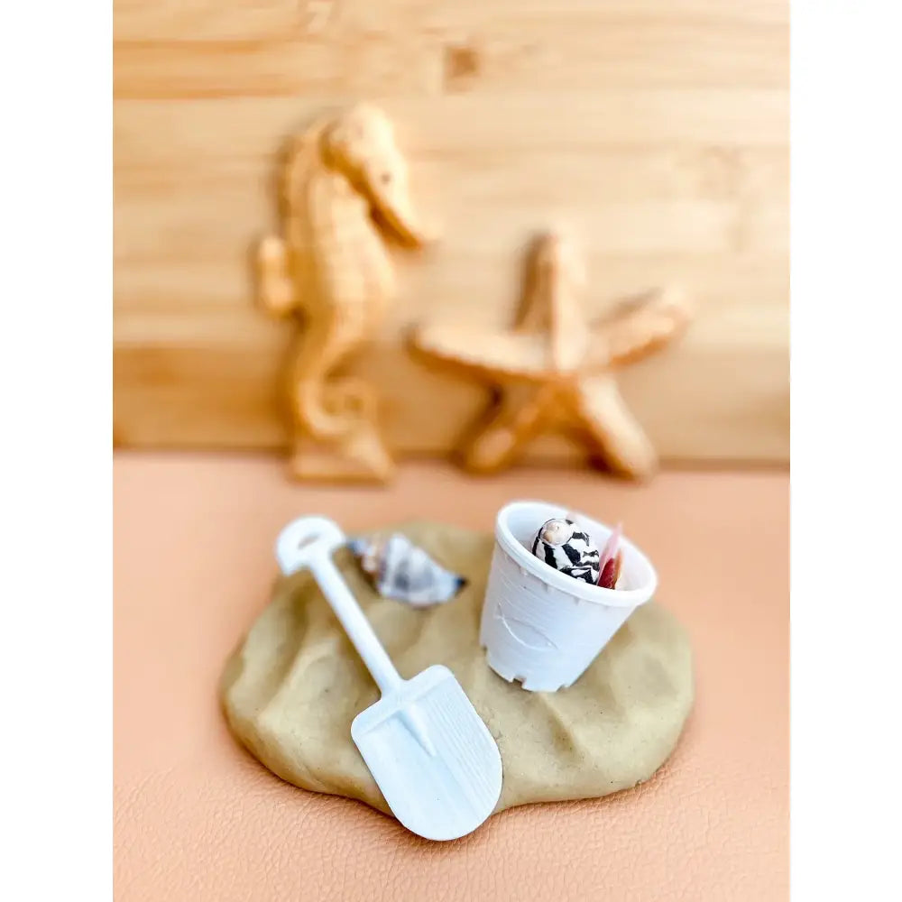 Sand-colored clay or dough with miniature beach-themed items placed on it.