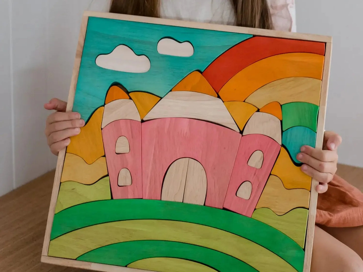 Colorful wooden puzzle depicting a whimsical landscape with a castle, rainbow, and clouds.