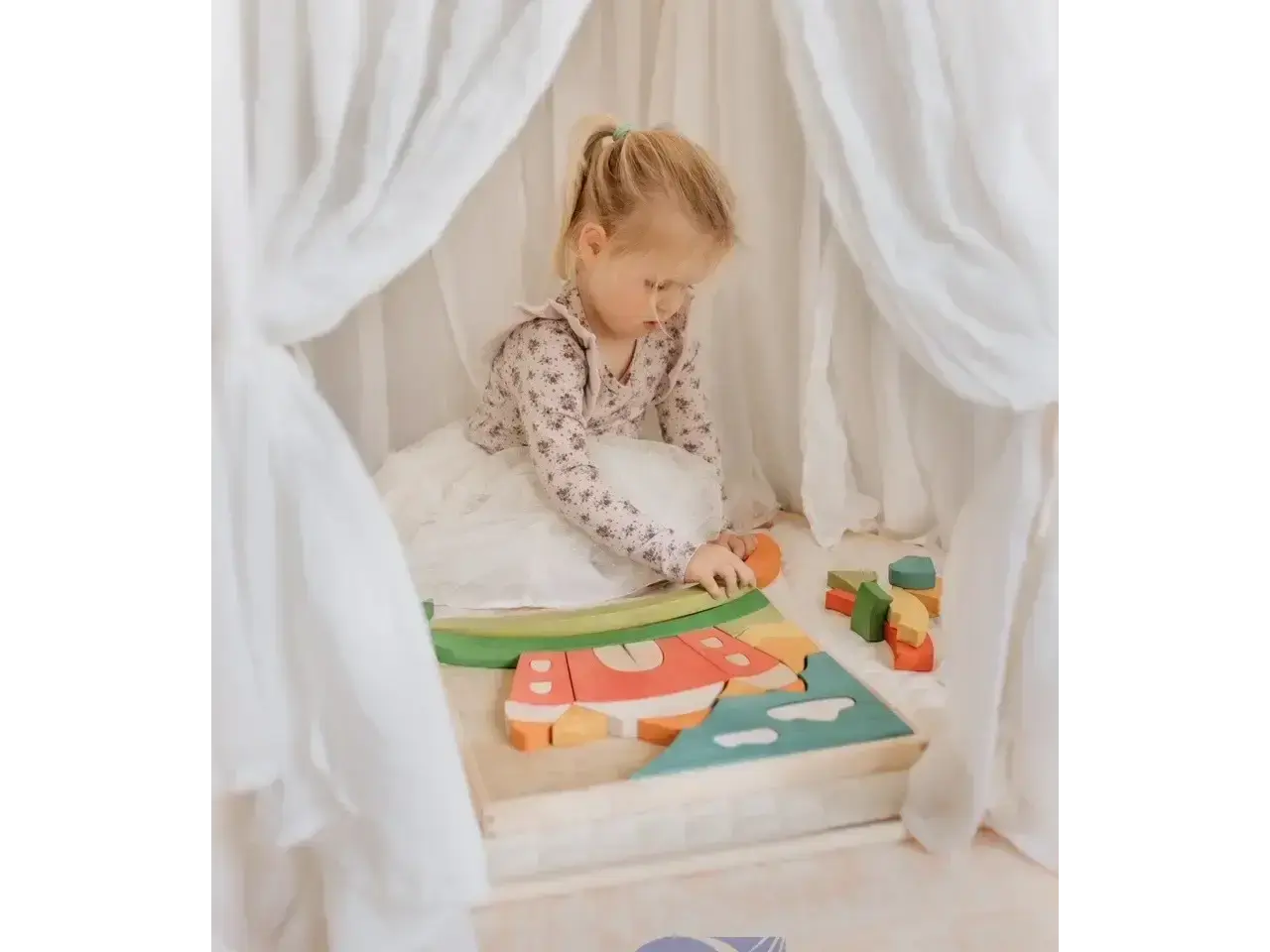 Child playing with a wooden puzzle or shape-sorting toy.