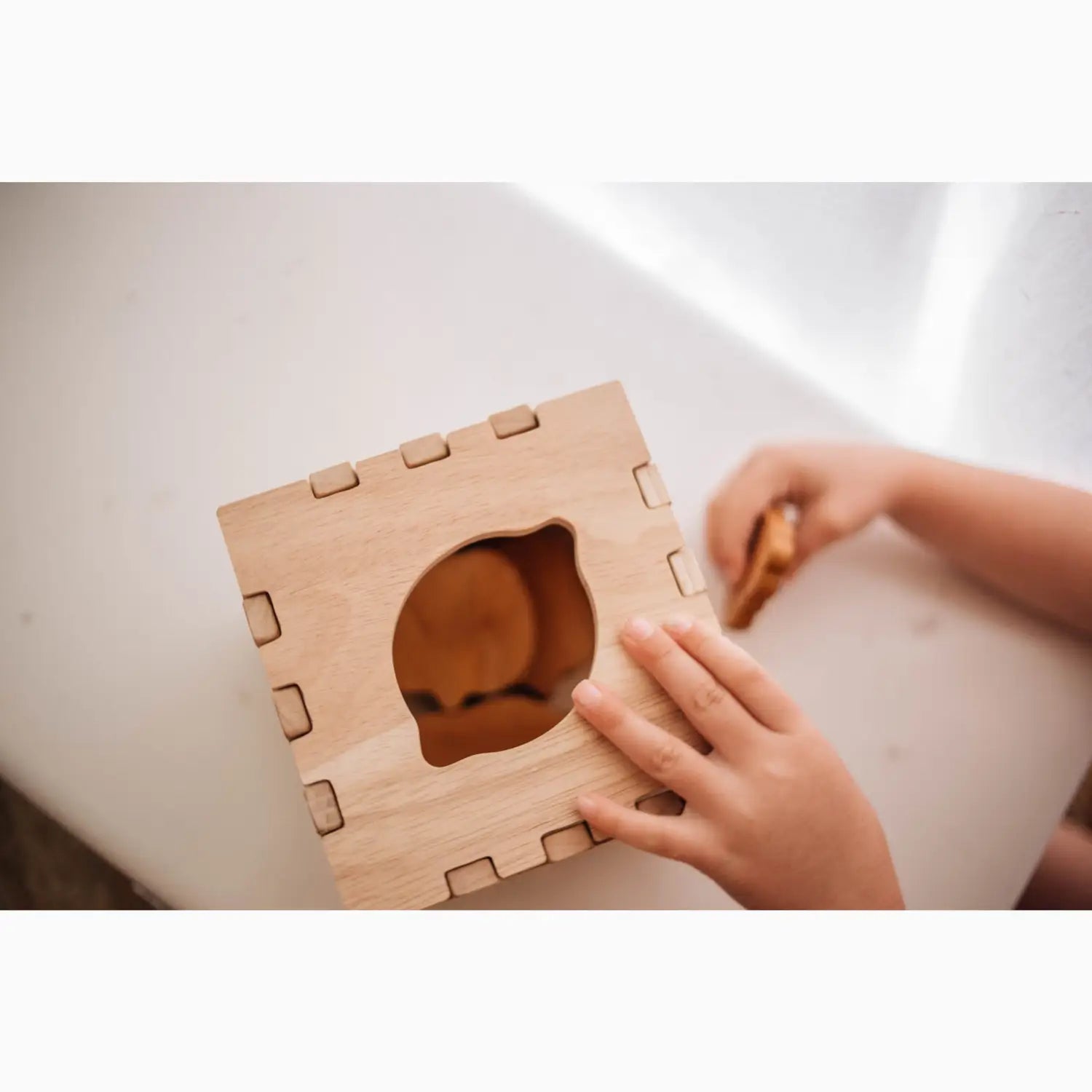 Wooden toy box with organic-shaped opening.