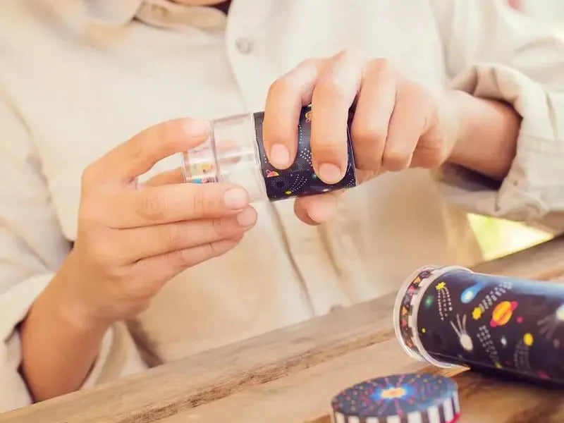 Child’s hands opening a colorful tin container.