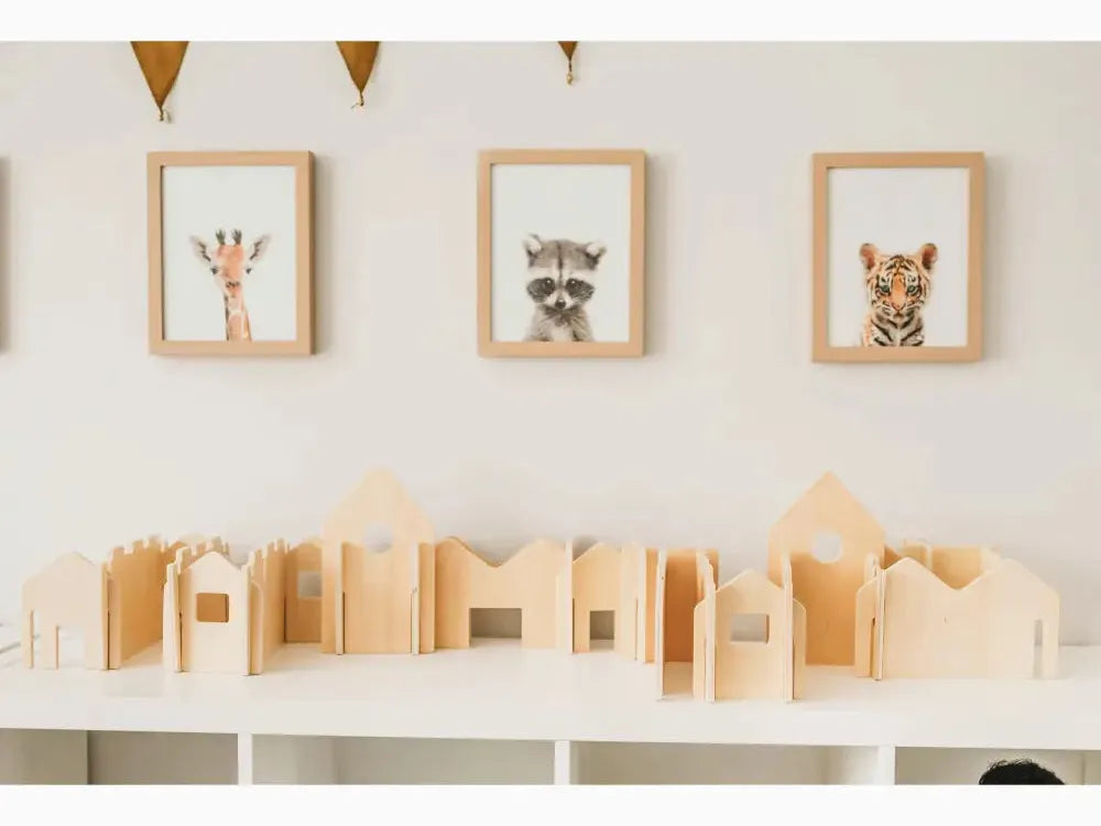 Wooden toy buildings or blocks arranged on a white surface.