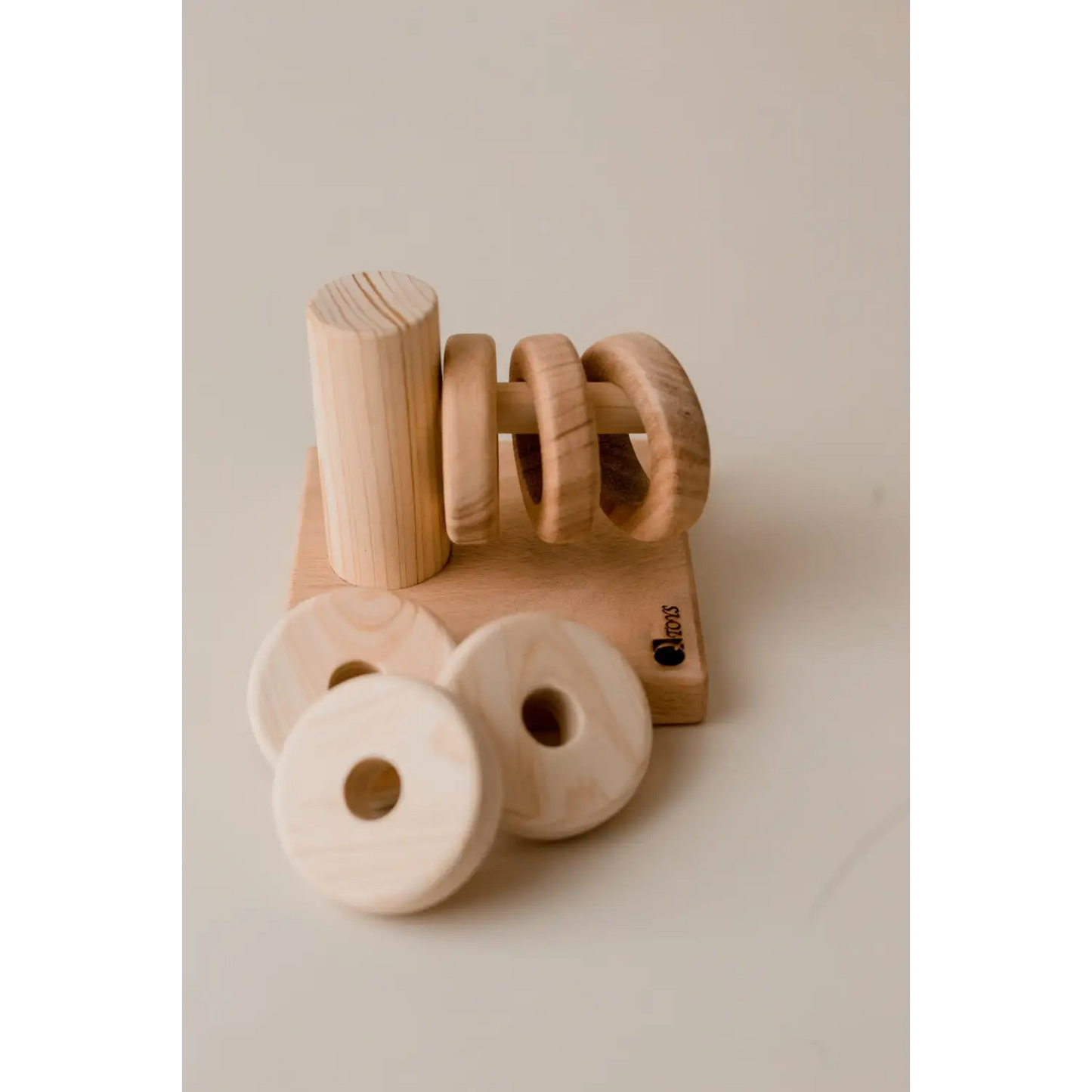 Wooden toy or puzzle piece shaped like the word ’no’ alongside circular wooden elements.