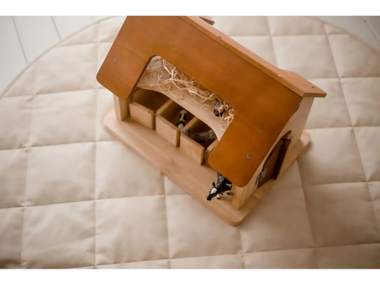 Wooden toy barn or stable with a peaked roof and openings.