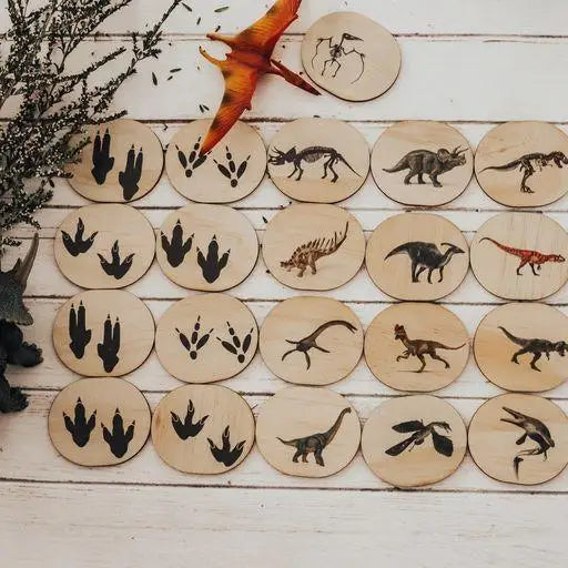 Collection of wooden discs with dinosaur and footprint designs burned or etched onto them.