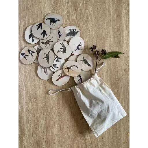 Set of wooden discs with dinosaur silhouettes painted on them, spilling from a cloth bag.