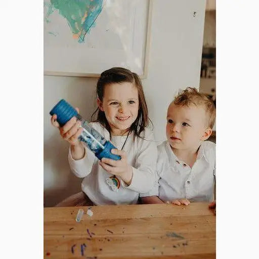 Two children playing with a blue paint bottle.