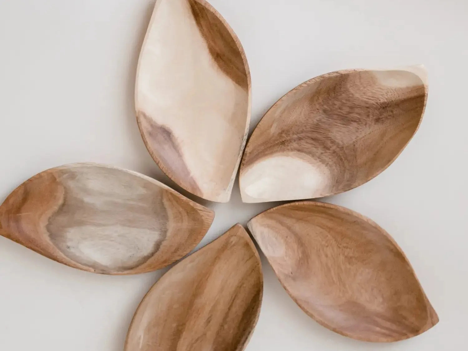 Flower-shaped arrangement of five wooden or ceramic petal-like pieces.