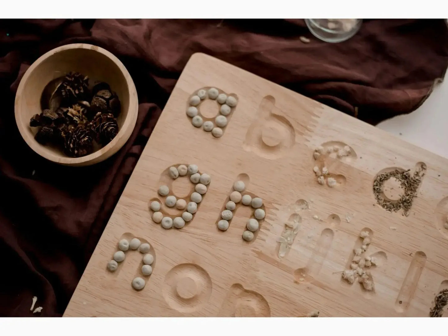 Wooden board with letters formed from small stones or pebbles.