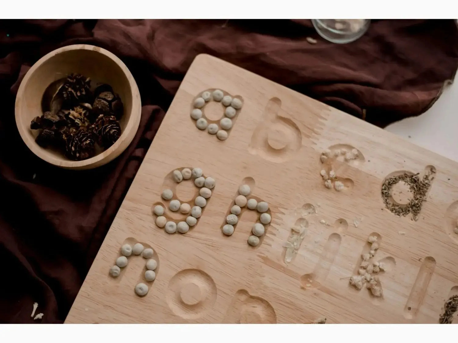 Wooden board with letters formed from small stones or pebbles.